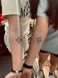 two people holding hands with tattoos on their arms