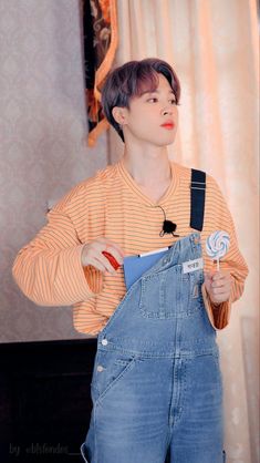 a person wearing overalls and holding a lollipop