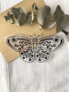 a paper cut out of a butterfly sitting on top of a table next to some leaves