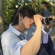 a young man holding a camera up to his face while another person takes a photo