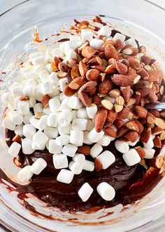 a bowl filled with marshmallows, chocolate sauce and chopped almonds on top