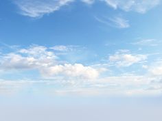 two people standing on the beach looking out at the ocean and clouds in the sky