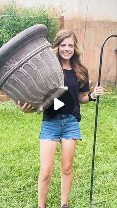 a woman is holding a large pot in her hands and standing on the grass outside