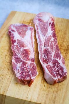 two pieces of raw meat sitting on top of a cutting board next to each other