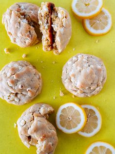 some oranges and cookies are on a yellow surface with one cut in half to show the inside