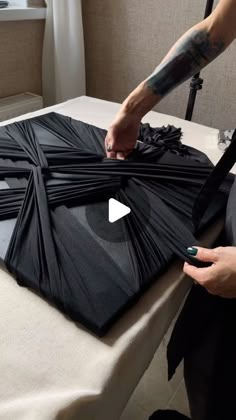 a person cutting up black paper on top of a table