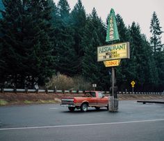 an old red pickup truck parked in front of a restaurant with a sign on it's roof