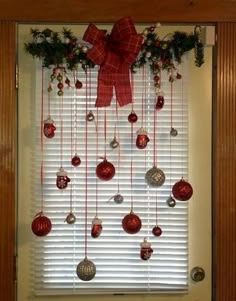 christmas decorations hanging on the window sill with red bows and baubles attached to it