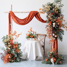 an orange and white wedding set up with flowers, greenery and candles on the table