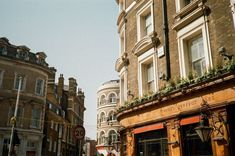 an old building on the corner of a city street with people walking by and buildings in the background