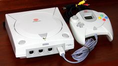 two video game controllers sitting next to each other on a wooden table with wires plugged into them