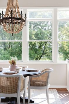 a dining room table with four chairs and a chandelier hanging from the ceiling