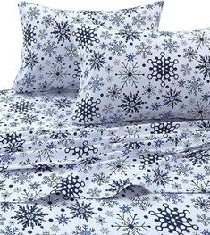 a bed with snowflakes on it and two pillows next to eachother