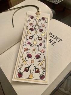 a bookmark with flowers on it sitting on top of an open book