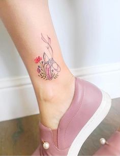 a woman's foot with a flower tattoo on her left ankle and pink shoes