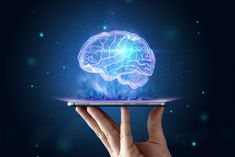 a hand holding a tablet with a glowing brain on it