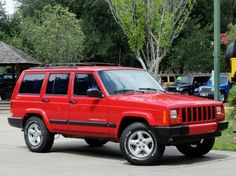 a red jeep is parked in a parking lot