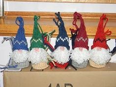 six knitted gnomes sitting on top of a cardboard box