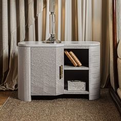 a white cabinet with two books on it and a lamp in the corner next to it