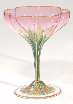 a pink glass vase sitting on top of a white table next to a green and gold plate