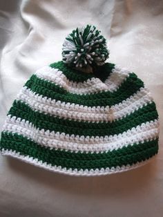 a green and white knitted hat with a pom - pom on top