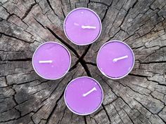 four purple candles sitting on top of a tree stump