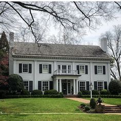 a large white house sitting on top of a lush green field