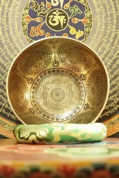 an ornately decorated gold plate sits in front of a colorful wallpapered background