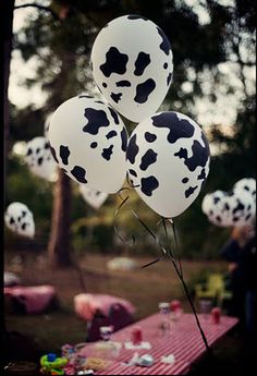 several balloons with black and white spots on them are in front of a picnic table