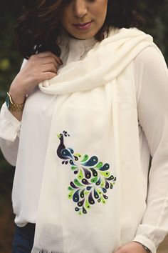 a woman wearing a white scarf with a peacock on it