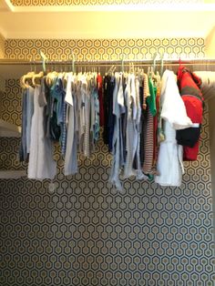 clothes are hanging on the rail in front of wallpaper