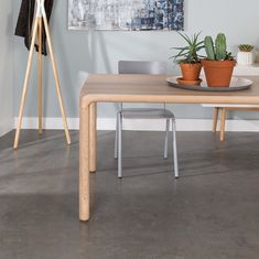 a wooden table with two potted plants on top of it next to a white wall