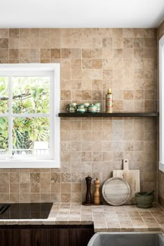 a kitchen with tiled walls and counter tops in front of a window that looks out onto the jungle