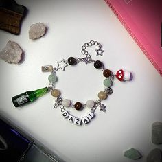 a personalized charm bracelet with wine bottles and charms on it, next to rocks