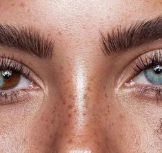 a woman's blue eyes with freckles on her eyebrows and long eyelashes