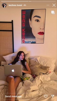 a woman laying in bed with a laptop on her lap and an advertisement behind her