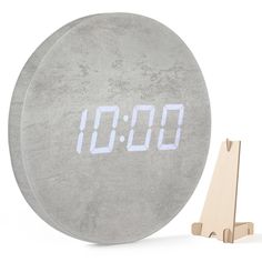 an alarm clock next to a wooden stand with it's digital numbers on it