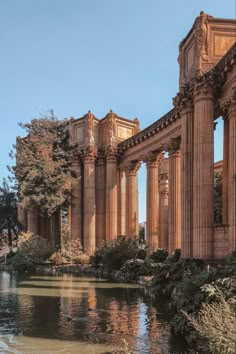 an old building sitting next to a body of water with trees in the foreground