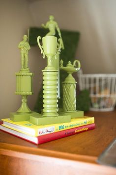 a stack of books sitting on top of a wooden table next to a green vase