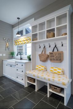 a kitchen with white cabinets and yellow cushions on the bench in front of the sink