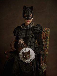 a woman sitting in a chair with a cat on her lap and wearing a mask