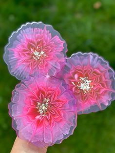 three pink flowers are being held up in the air