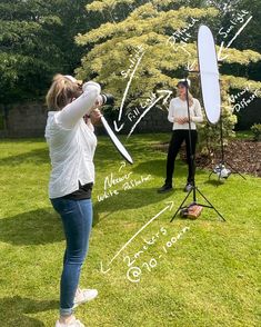 two women are standing in the grass and one is holding a large object with writing on it