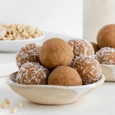 a white bowl filled with sugar covered donuts next to other bowls full of nuts