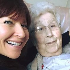 an older woman is smiling next to a younger woman who has her arm around her shoulder