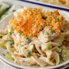 a white plate topped with pasta covered in chicken and cheese sauce next to asparagus