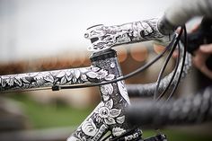 the handlebars on this bike are decorated with black and white floral designs,