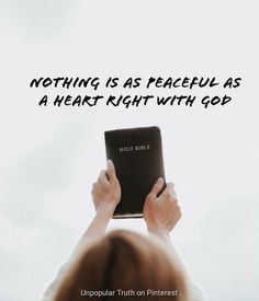 a person holding up a book with the words nothing is as peaceful as a heart right with god