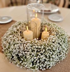 three candles are placed in the center of a wreath with baby's breath flowers