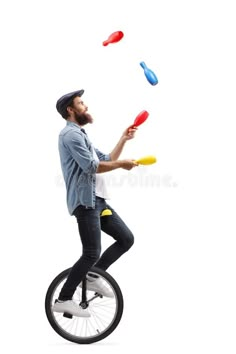 a man riding on top of a unicycle and juggling through the air